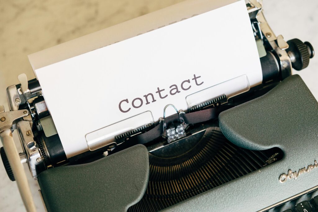 Close-up of a vintage typewriter with paper displaying the word 'Contact'.